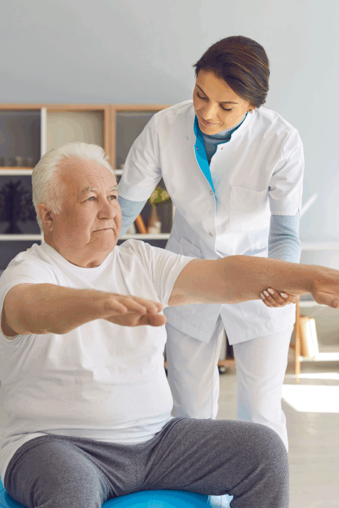 Physical therapist helping an older adult practice balance exercises indoors to prevent winter falls and build leg strength.