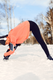 Physical therapist helping an older adult practice balance exercises indoors to prevent winter falls and build leg strength.