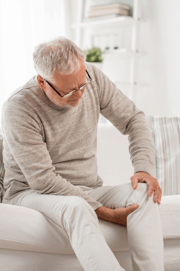 Person outdoors in winter holding their knee due to stiffness.