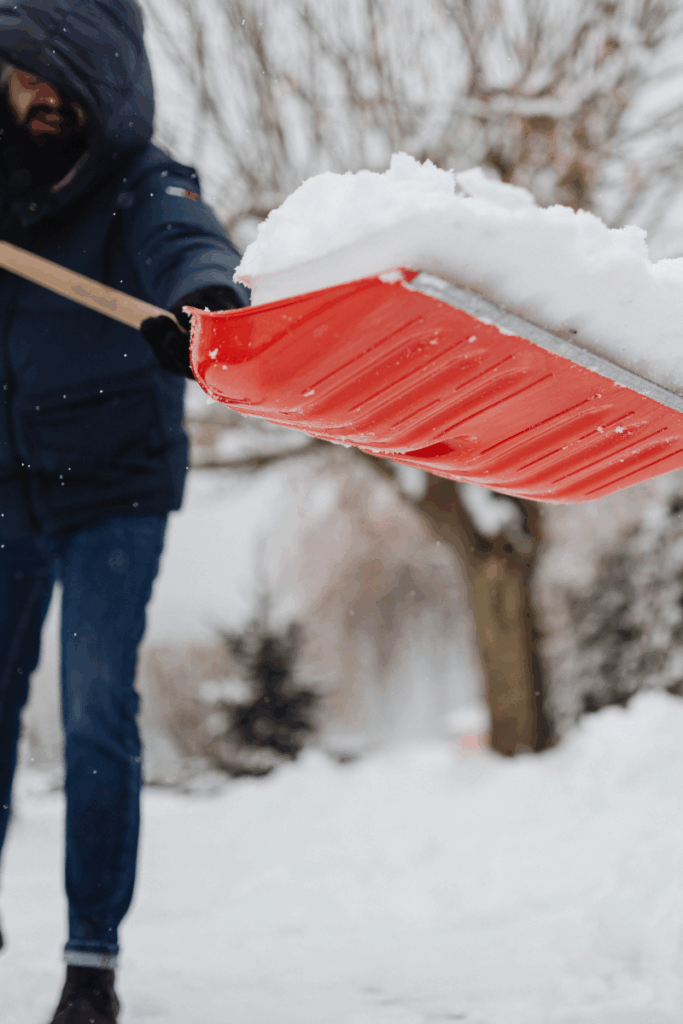 Person warming up indoors before shoveling to prevent winter back pain.