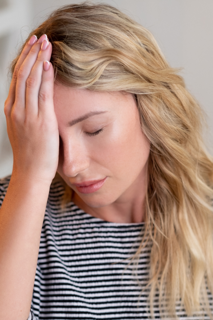 Woman sitting at her desk holding her head with chronic headache and neck tension symptoms she thought were normal