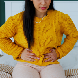 Woman holding her lower stomach, showing discomfort that may relate to pelvic floor problems.