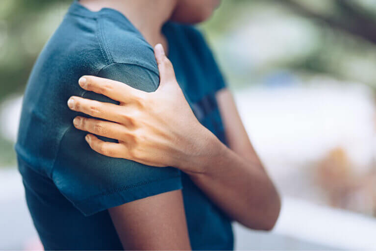 Person experiencing shoulder pain while lifting arm, seeking treatment at Reform Physical Therapy